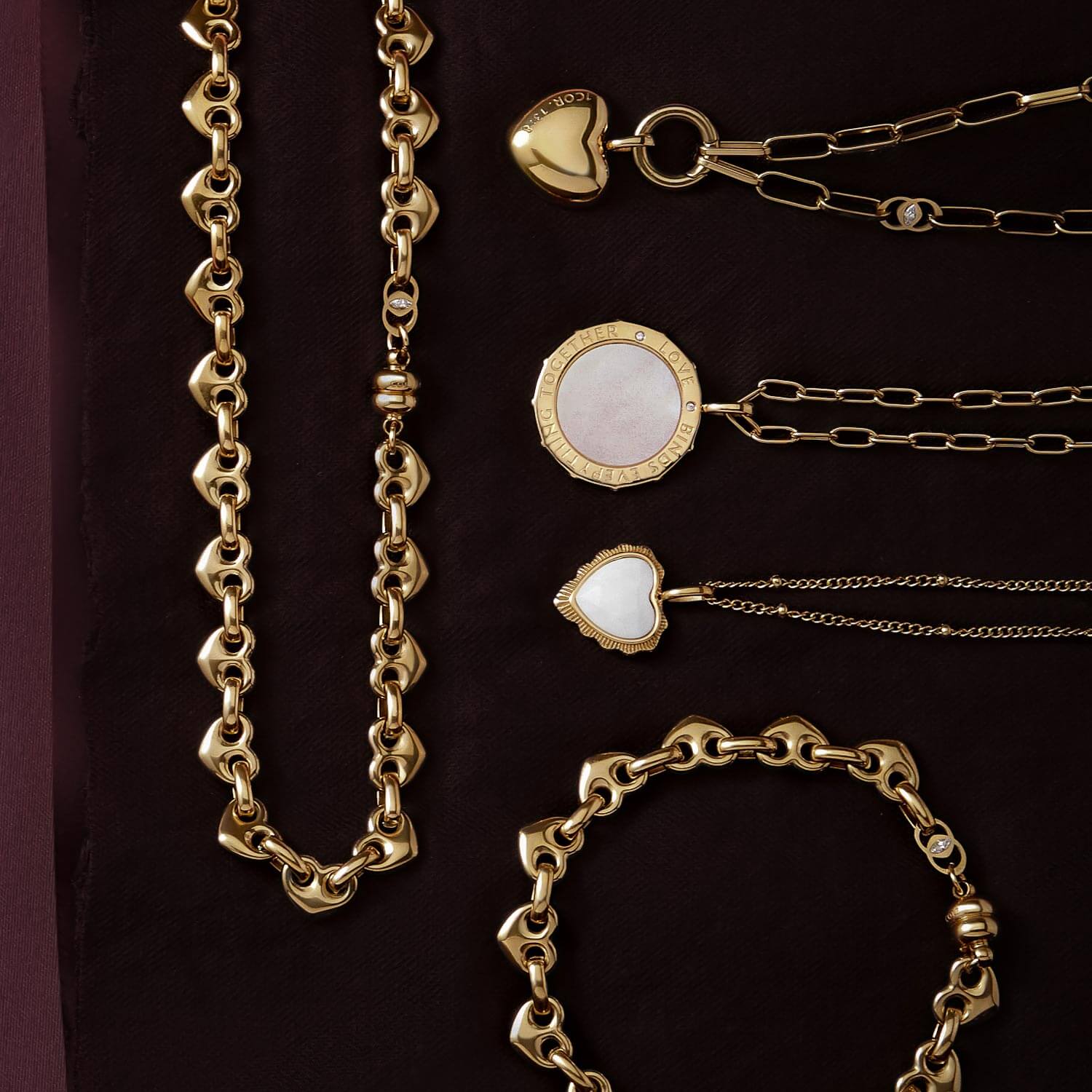Gold Love scripture necklaces and matching bracelet with heart and mother-of-pearl pendants on burgundy 